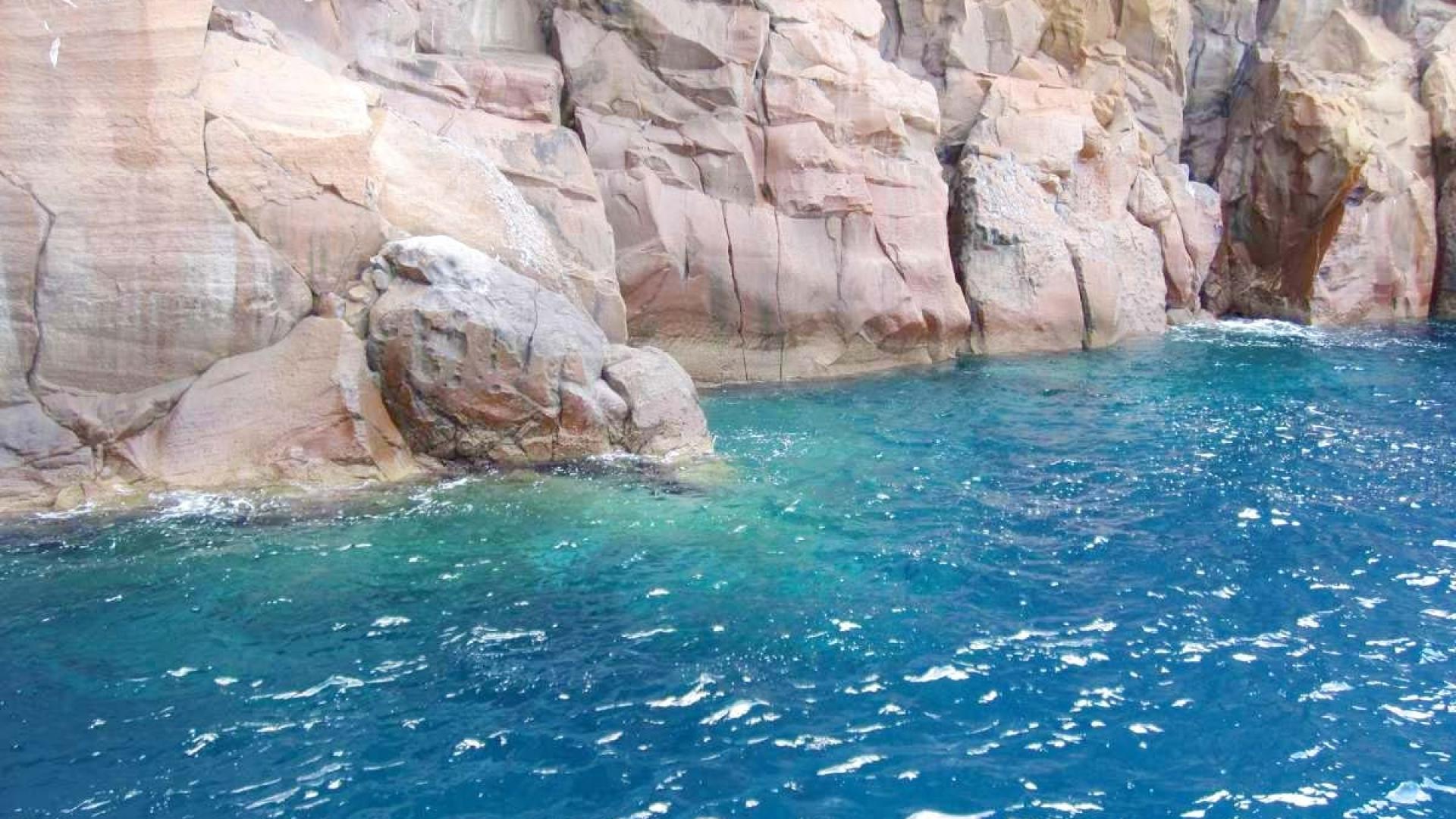 Scogliere imponenti si tuffano in un mare blu profondo, evocando serenità e potenza naturale.