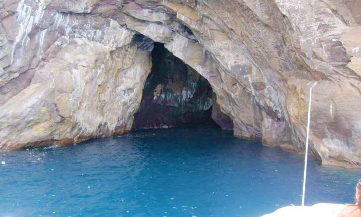 Grotta marina con acqua blu intenso, atmosfera misteriosa e avventurosa, incastonata nella roccia.