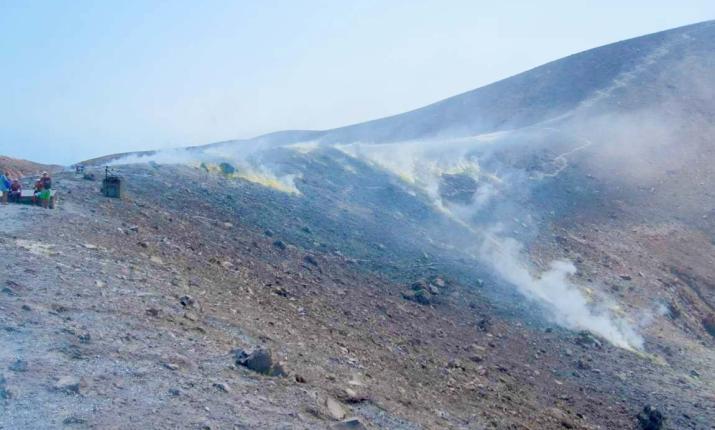 Paesaggio vulcanico fumante, terreno arido e roccioso, atmosfera surreale e affascinante.