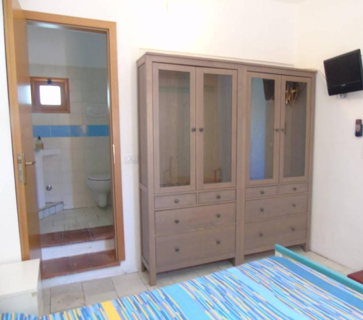 Camera luminosa con armadio grande, bagno privato e TV, atmosfera accogliente e rilassante.