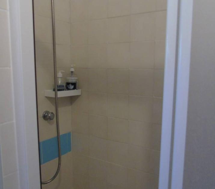 Doccia semplice, piastrelle beige e blu, atmosfera tranquilla e minimalista.
