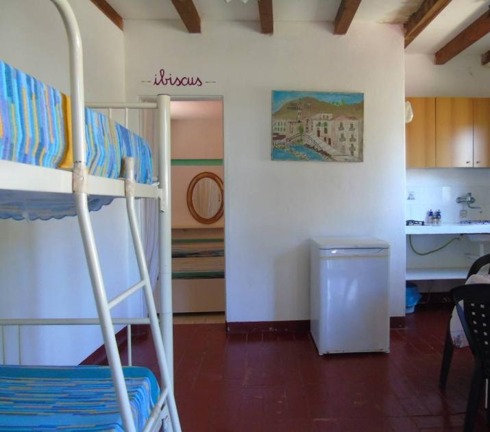 Interno accogliente con letti a castello, cucina semplice, atmosfera rilassata e familiare.