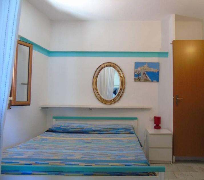 Camera accogliente, letto colorato, specchio dorato, atmosfera serena e luminosa, dettagli vivaci.