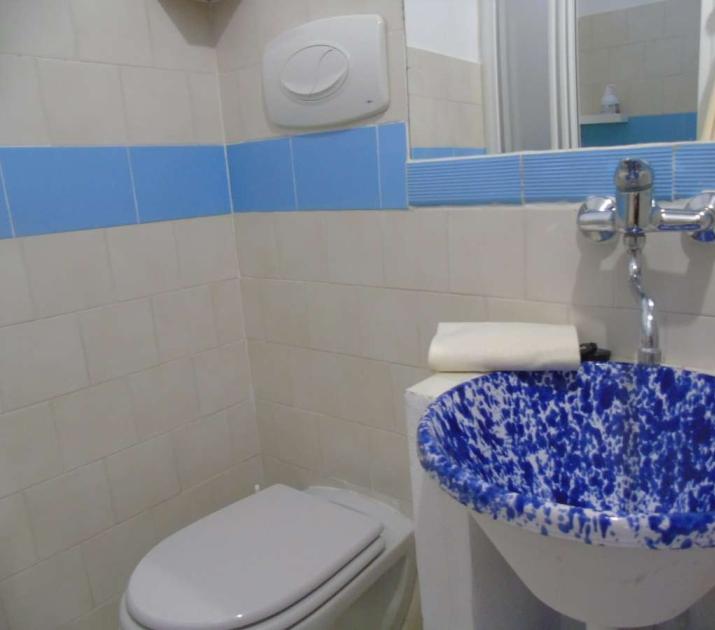 Bagno semplice, lavabo blu artistico, piastrelle azzurre, atmosfera pulita e accogliente.
