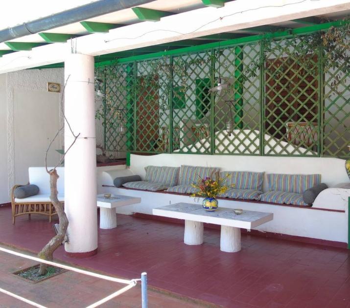 Terrazza accogliente con divano colorato, vasi decorativi e atmosfera rilassante.