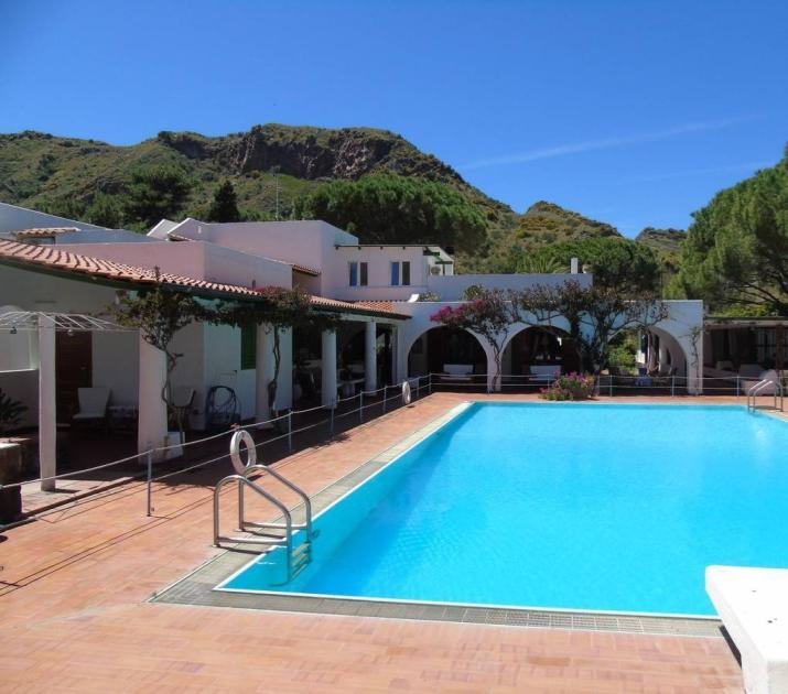 Piscina azzurra, villa bianca, montagne verdi: un'oasi di tranquillità e bellezza mediterranea.