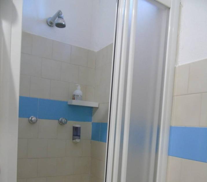Doccia minimalista, piastrelle beige e blu, sensazione di pulizia e tranquillità.