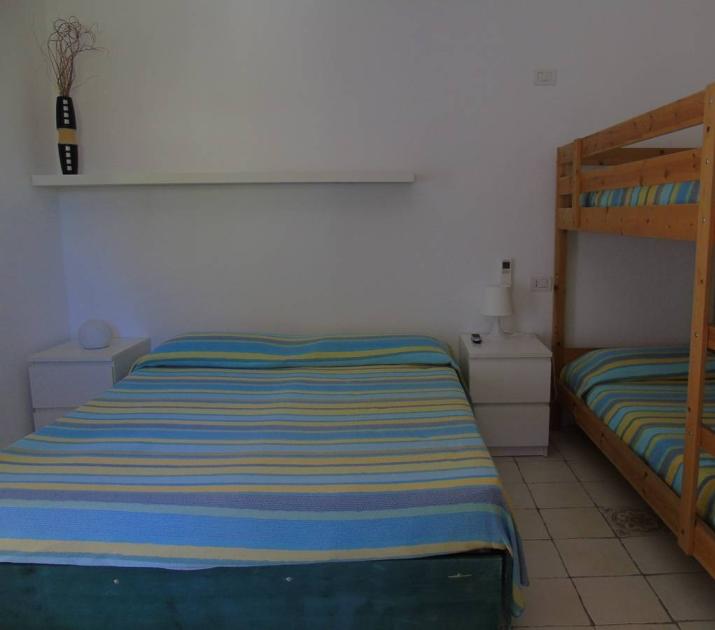 Camera accogliente con letto matrimoniale e letti a castello, atmosfera rilassante e semplice.