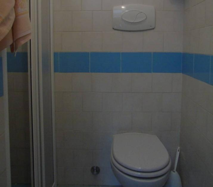 Bagno semplice e ordinato, piastrelle bianche e azzurre, atmosfera tranquilla e pulita.