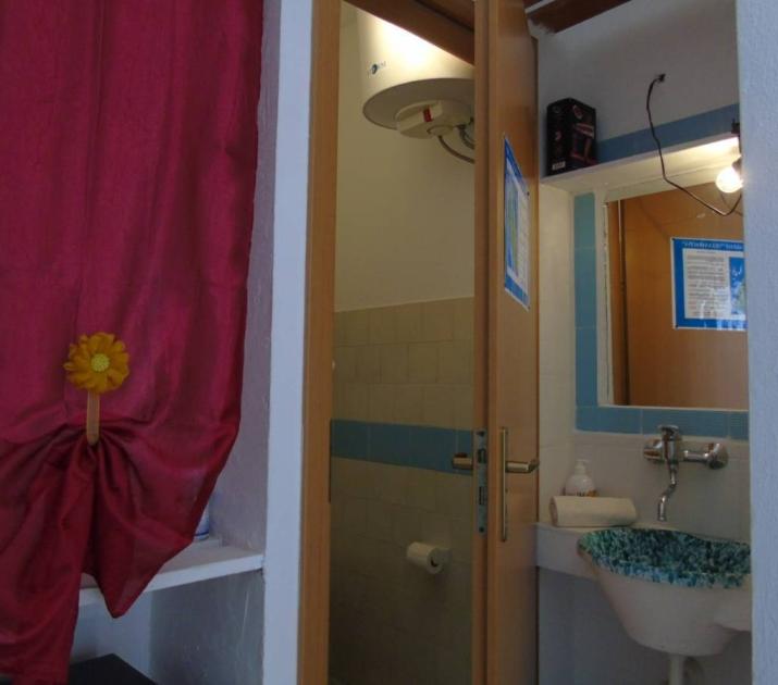 Bagno accogliente con tenda rossa, lavandino artistico e decorazione floreale.