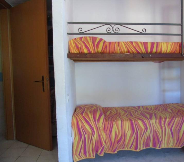 Letto a castello colorato, atmosfera calda e accogliente, scala in legno rustica.