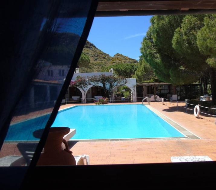 Piscina blu, sole splendente, natura verde, pace e relax in un'oasi mediterranea.