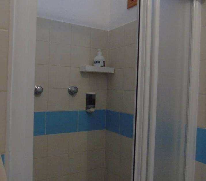 Doccia semplice, piastrelle beige e blu, atmosfera intima e rassicurante.