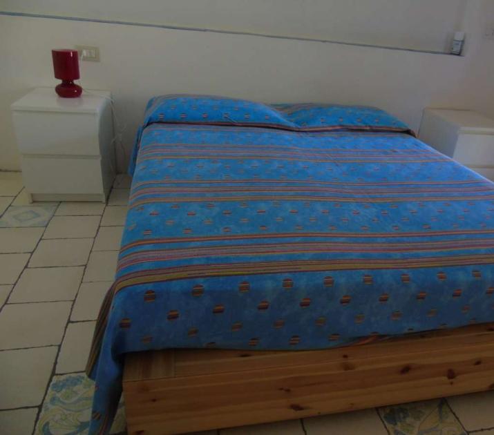 Camera accogliente con letto blu, lampada rossa e atmosfera serena.