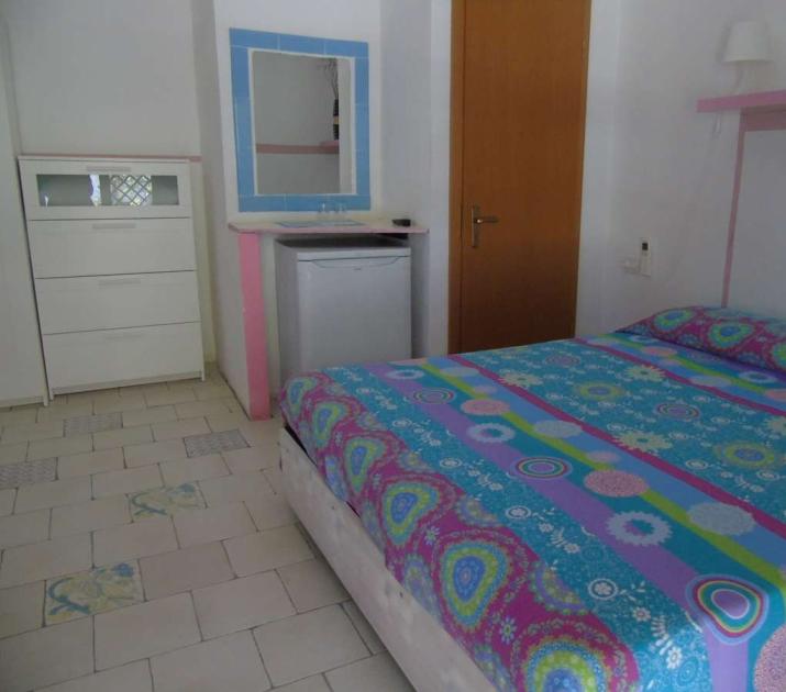 Camera accogliente, letto colorato, arredo semplice, atmosfera serena e ordinata.