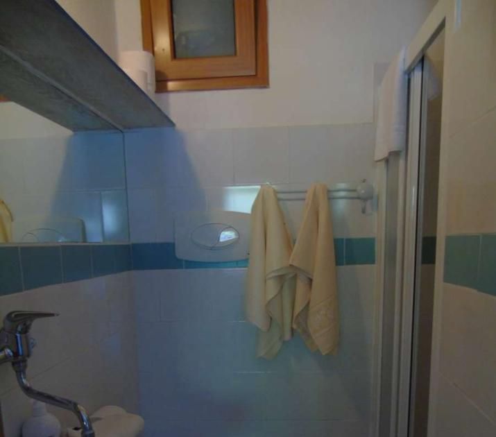 Bagno piccolo, accogliente, con lavandino decorato e asciugamani appesi, atmosfera intima e calda.