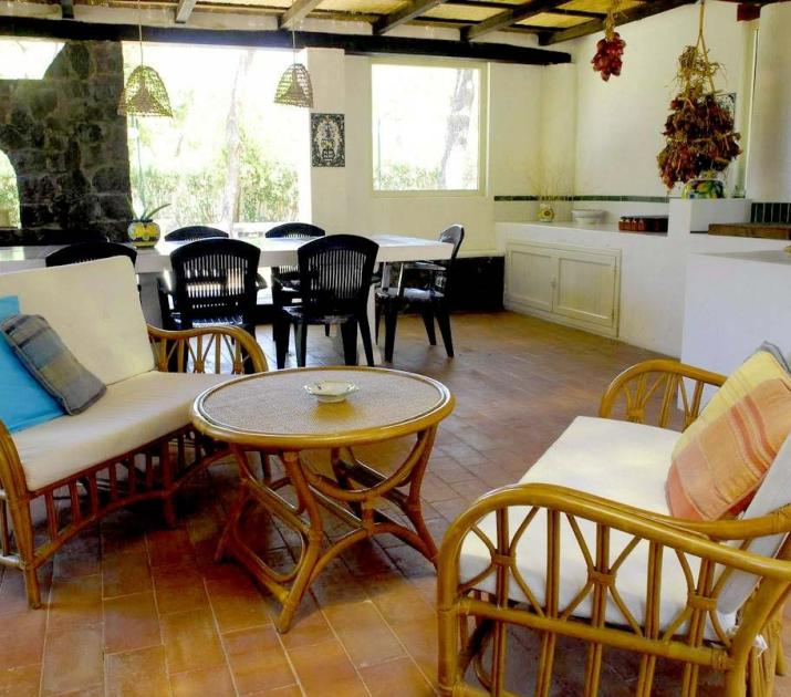 Accogliente veranda con arredi in rattan, atmosfera rustica e calda, dettagli naturali e rilassanti.