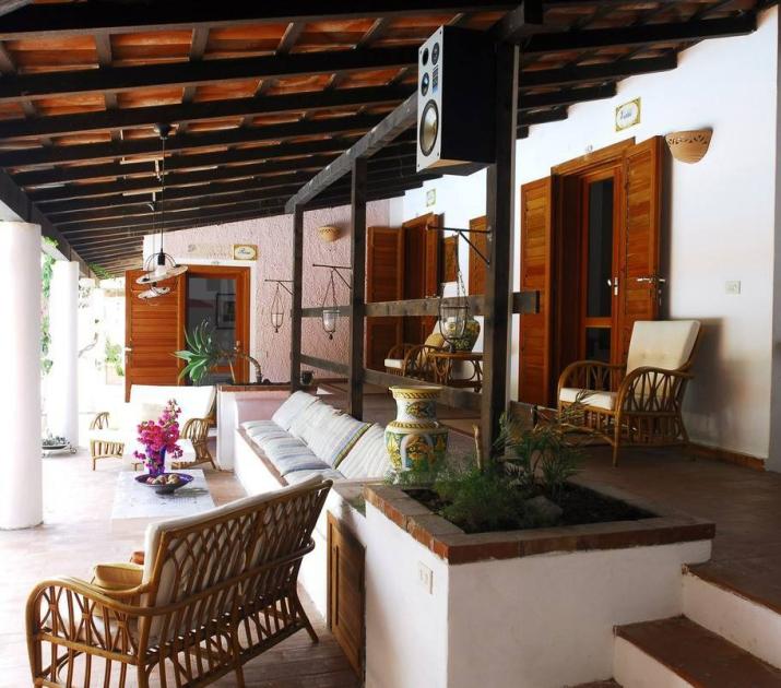 Terrazza accogliente con sedie in vimini, fiori vivaci e atmosfera rilassante.