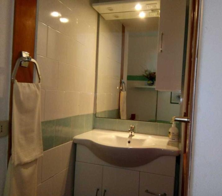 Bagno accogliente con specchio, lavandino bianco e luce soffusa, atmosfera tranquilla.