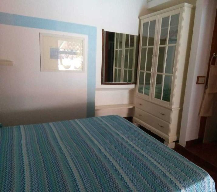 Camera accogliente con letto a righe blu, armadio bianco e atmosfera serena.