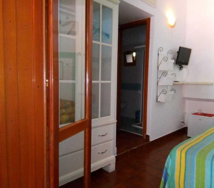 Camera accogliente con arredi colorati, piccola TV e bagno annesso.