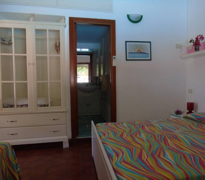 Camera colorata e accogliente con letto matrimoniale, armadio e bagno luminoso.