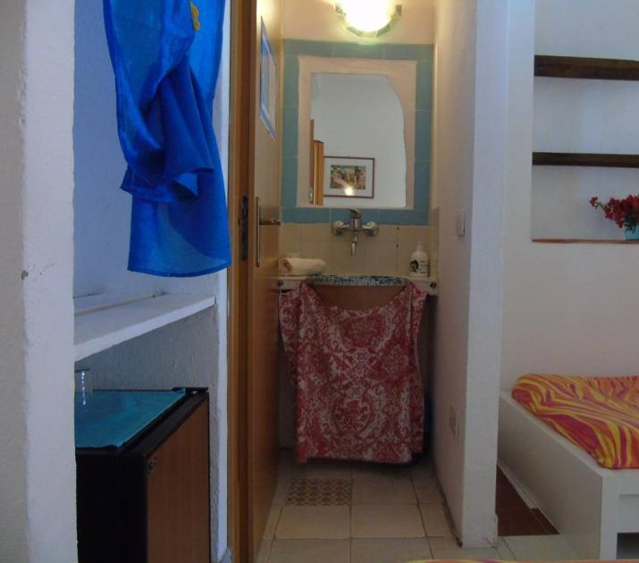 Stanza accogliente con letto colorato, lavandino decorato e atmosfera serena e luminosa.