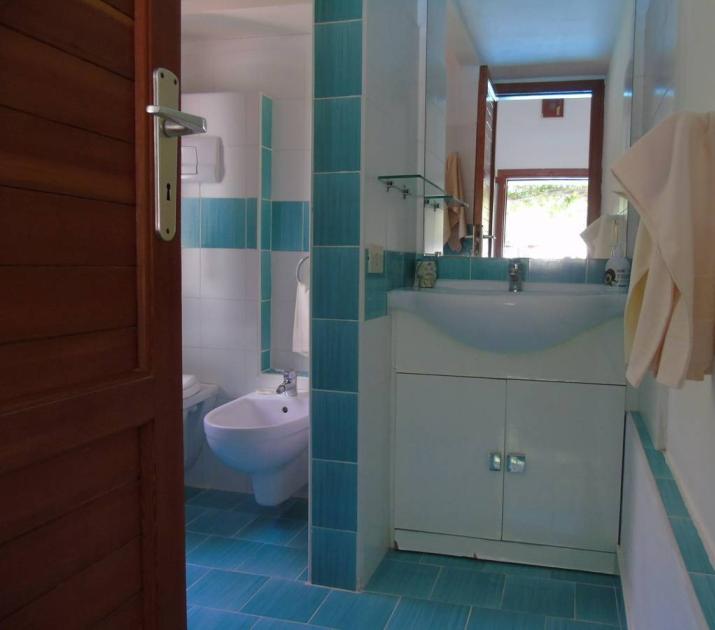 Bagno luminoso con piastrelle blu, lavabo bianco, asciugamani ordinati, atmosfera fresca e pulita.