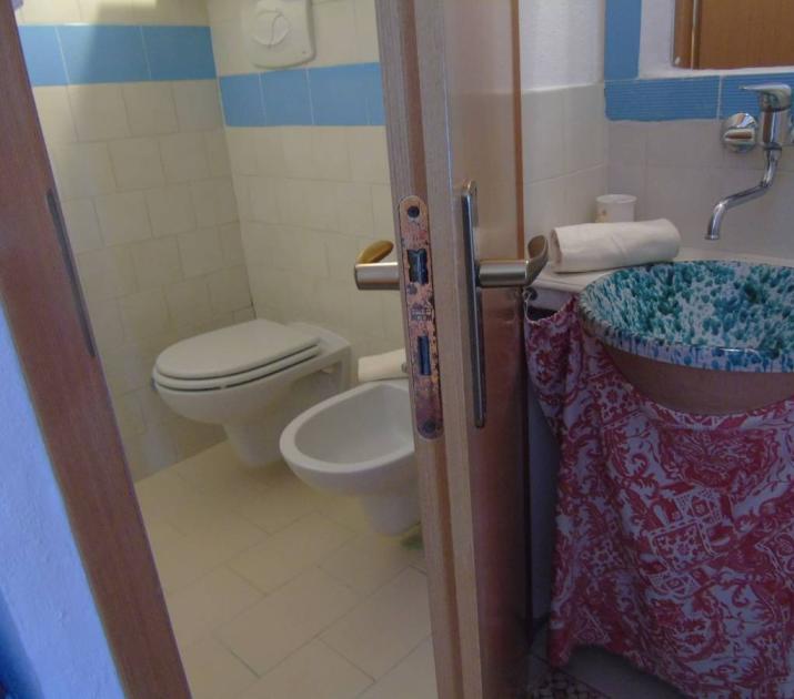Bagno piccolo e colorato con lavabo artistico, trasmette accoglienza e vivacità.