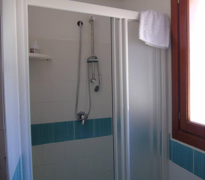 Doccia luminosa con piastrelle blu, finestra e asciugamano appeso, atmosfera fresca e pulita.