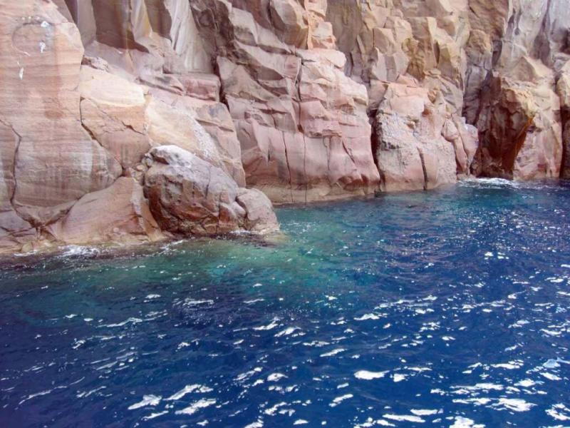 Scogliere rosate a picco su un mare blu intenso, evocano serenità e meraviglia naturale.