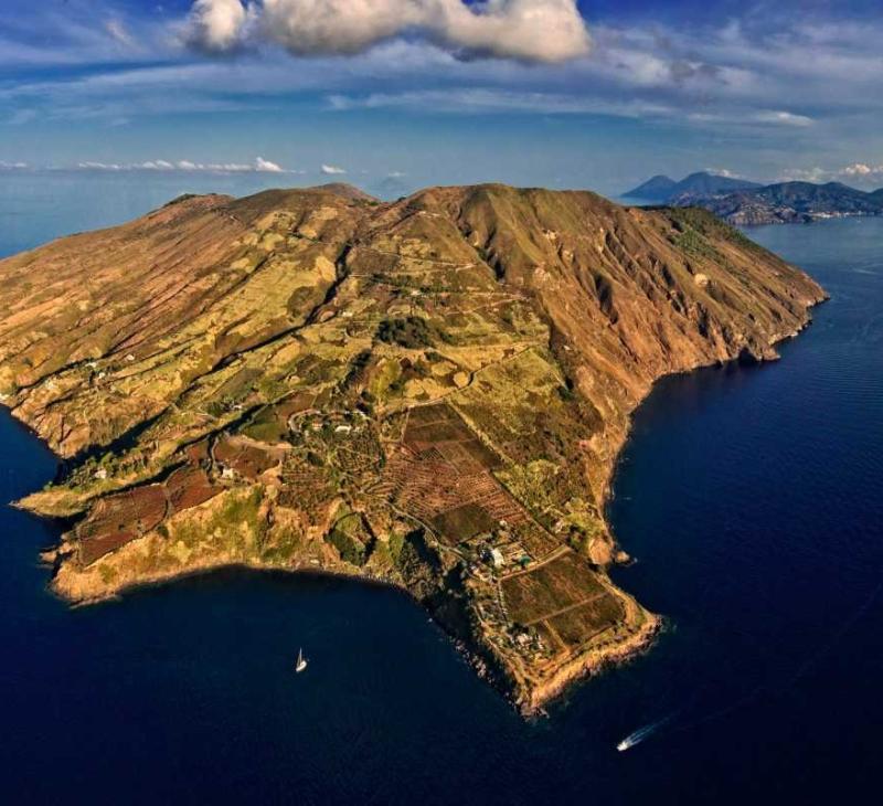 Un'isola verdeggiante baciata dal sole, circondata da un mare blu profondo e sereno.